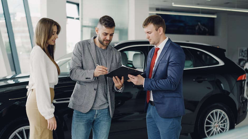 Three adults discussing documents at a car dealership beside a black car