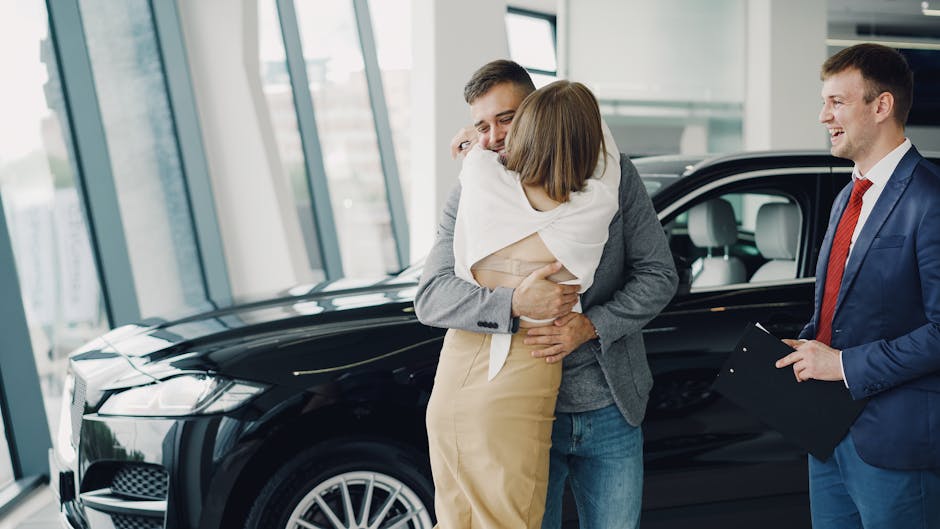 A couple embraces joyfully in a car showroom after purchasing a new vehicle.